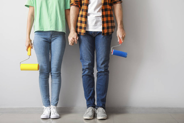 Young couple with paint rollers near light wall in new apartment - Photo, Image