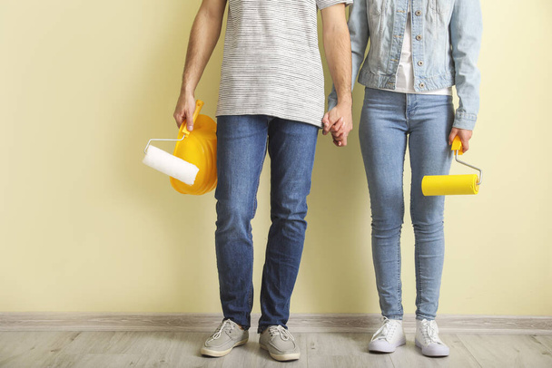 Young couple with tools near color wall in new apartment - Photo, Image