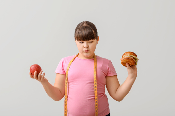Избыточный вес девушки со здоровой и нездоровой пищи на легком фоне
 - Фото, изображение