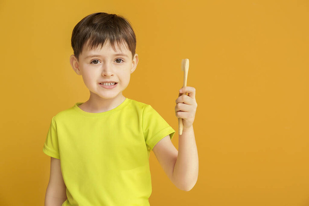 Χαριτωμένο αγοράκι με οδοντόβουρτσα στο φόντο χρώμα - Φωτογραφία, εικόνα