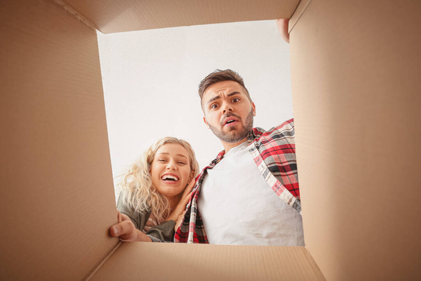 Emotional young couple with open moving box, view from inside - Foto, Bild