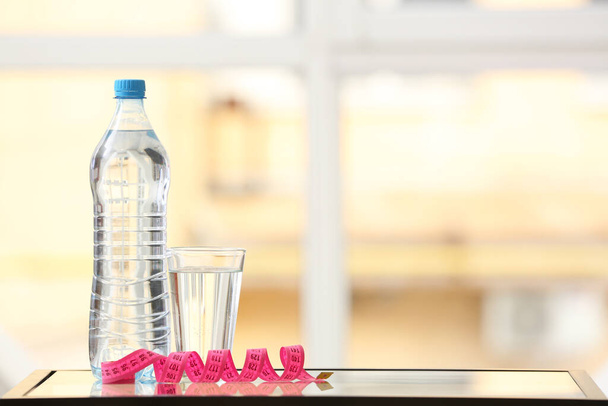 Szkło i butelka wody z taśmą pomiarową na stole - Zdjęcie, obraz