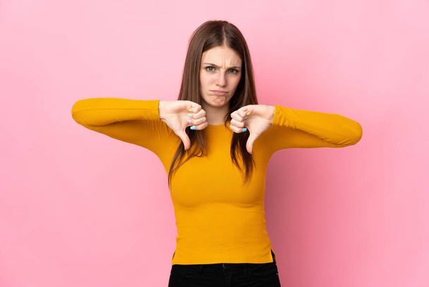 Young caucasian woman isolated on pink background showing thumb down with two hands - Foto, afbeelding