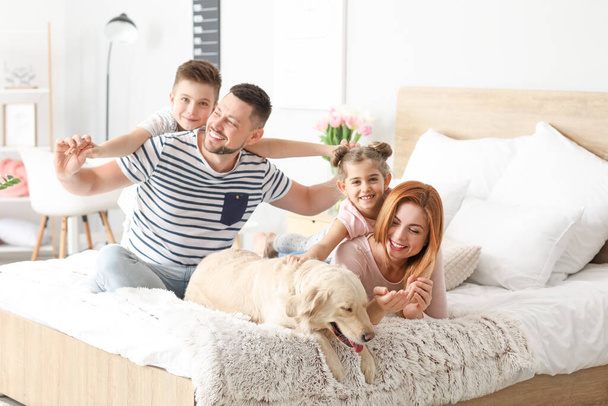 Familia feliz con perro en el dormitorio en casa
 - Foto, imagen