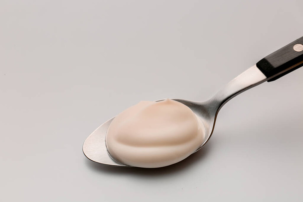 Cuchara con yogur fresco sobre fondo blanco
 - Foto, imagen