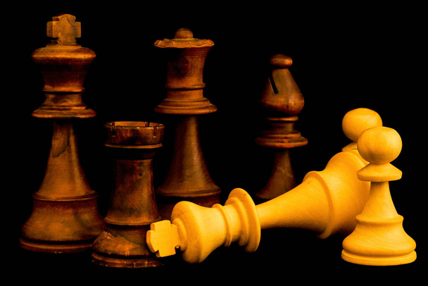 El equipo blanco se rinde al equipo negro al final del juego. Dos piezas estándar de ajedrez de madera sobre fondo negro
 - Foto, Imagen