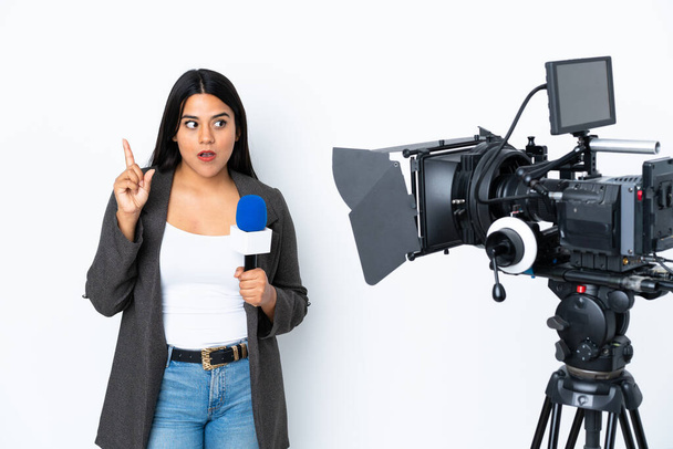 Reporter Colombian woman holding a microphone and reporting news on white background thinking an idea pointing the finger up - Fotografie, Obrázek