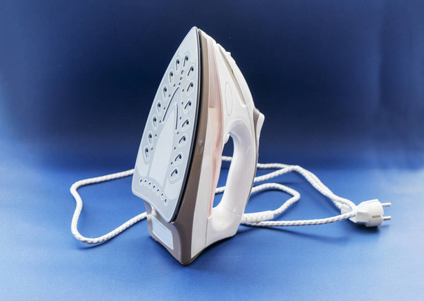 Modern steam electric iron in white on a blue background. - Photo, Image