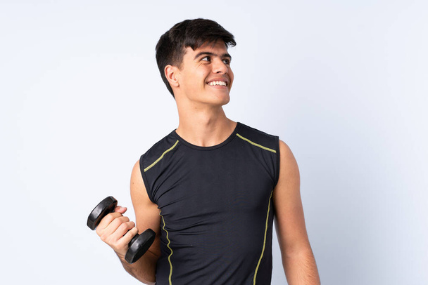 Sport uomo rendendo sollevamento pesi su isolato sfondo blu guardando mentre sorride
 - Foto, immagini