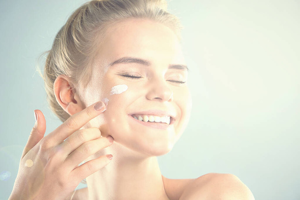 moisturizing summer skin care sunscreen. beautiful model applying cosmetic cream treatment on her face. rays of the sun illuminate the happy face of young women - Zdjęcie, obraz