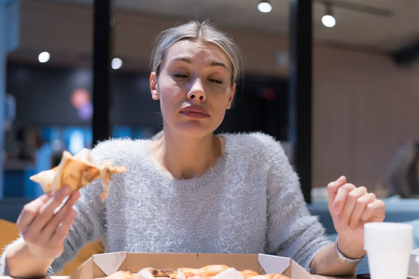 Mulher bonita comer pizza e beber cola enquanto sentado dentro expres restaurante tarde da noite
. - Foto, Imagem