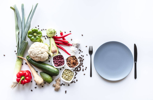 Top view of fresh group of vegetables on white background with plate and cutlery . Copy space - Photo, Image