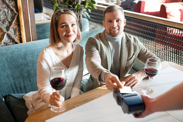 Férfi fizet az étkezésért randin egy nővel az étteremben a hitelkártyájával, vízszintes magas szögű lövés - Fotó, kép