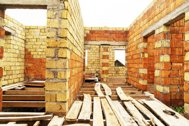 Unvollendeter Bau eines neuen Mehrfamilienhauses. Hauswand aus rotem Backstein im Bau. - Foto, Bild
