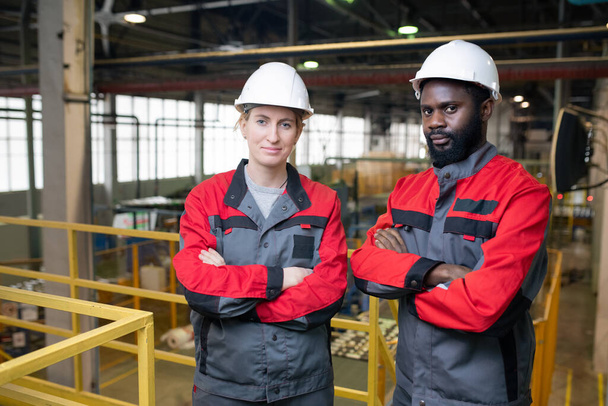 Portrait horizontal moyen de deux ingénieurs d'usine professionnels debout avec les bras croisés regardant la caméra
 - Photo, image