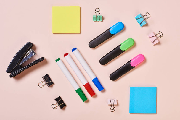 Highlighter pens, whiteboard markers, paper clips and sticker papers on pale pink background, flat lay shot - Fotoğraf, Görsel