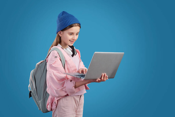 Contenido chica adolescente moderna con satchel navegar por Internet en el ordenador portátil contra el fondo azul
 - Foto, Imagen