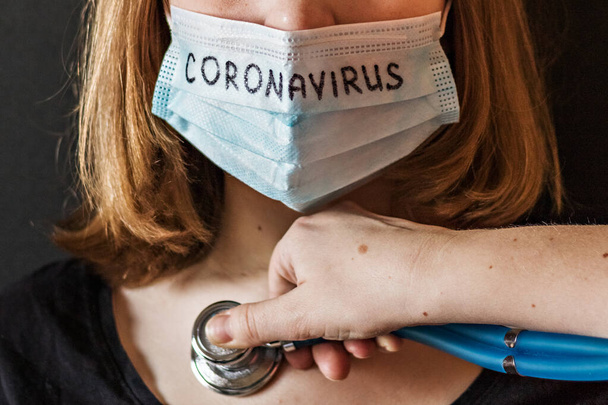 Een close-up portret van een meisje met een ijzig masker op haar gezicht met vermoedelijk coronavirus, dat de dokter met een stethoscoop beluistert. Nieuwe Coronavirus-covid-2019.Chinese uitbraak van coronavirus. - Foto, afbeelding