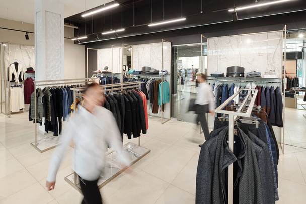 Movimiento borroso de los consultores de ventas en la tienda de ropa con estantes y accesorios en los estantes
 - Foto, imagen