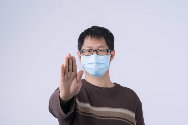 Portrait of young Asian man, saying no to coronavirus infection with wearing medical surgical blue face mask isolated on white background, close up, closeup. - Fotografie, Obrázek