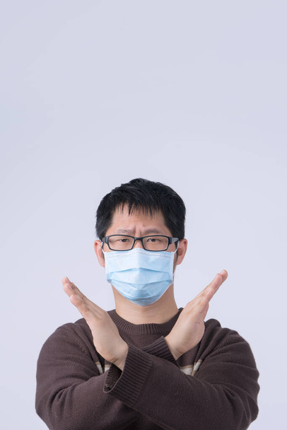 Portrait of young Asian man, saying no to coronavirus infection with wearing medical surgical blue face mask isolated on white background, close up, closeup. - Φωτογραφία, εικόνα
