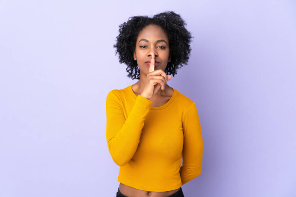 Young African American woman isolated on purple background showing a sign of silence gesture putting finger in mouth - Photo, Image