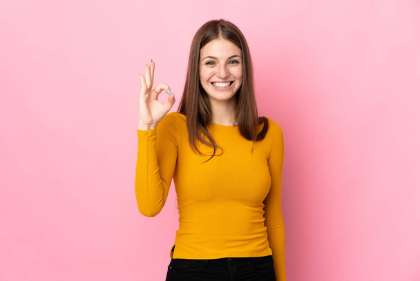 Jeune femme caucasienne isolée sur fond rose montrant ok signe avec les doigts - Photo, image