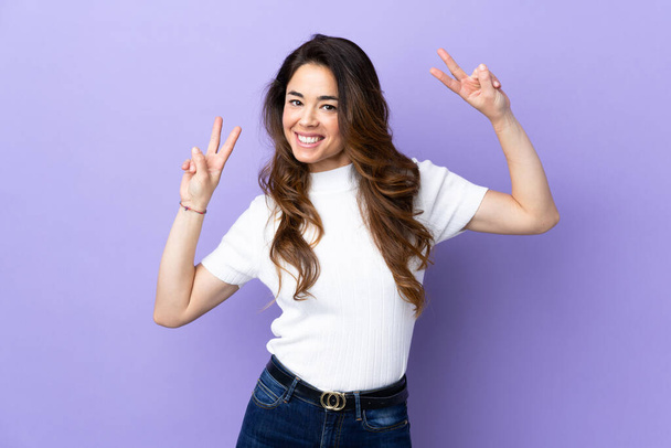 Woman over isolated purple background showing victory sign with both hands - Photo, Image