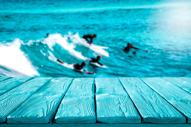 Surfers on waves in the turquoise ocean. Blue wooden table with space for your decoration and advertising products. Happy active sunny summer time and the ocean. Holidays. Vacation. - Photo, Image
