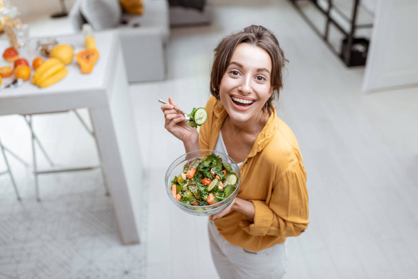 Donna che mangia insalata a casa - Foto, immagini