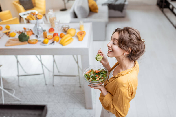 Жінка їсть салат вдома
 - Фото, зображення