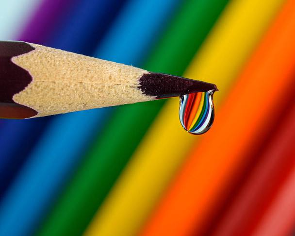 a drop of water on the tip of a pencil with a reflection of the colors of the rainbow - Foto, Imagem