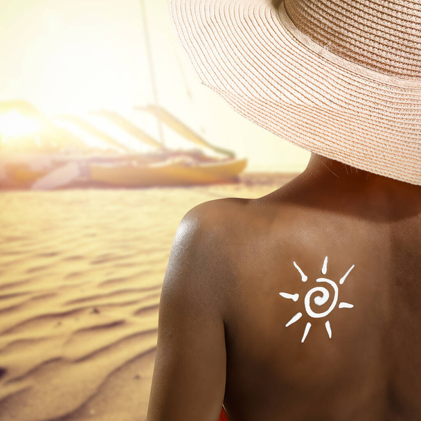 Frau mit Sonnencreme auf dem Rücken und sommerlichem Strandhintergrund. Raum für Ihre Dekoration oder Ihr Produkt.  - Foto, Bild