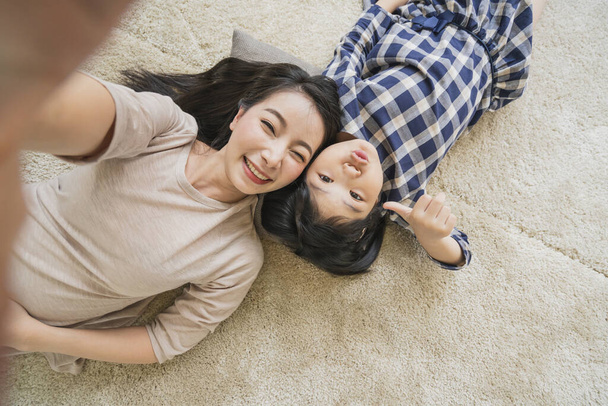 happy Asian Family mother  and daughter making a selfie photo while use  in living room home background. - Foto, Bild