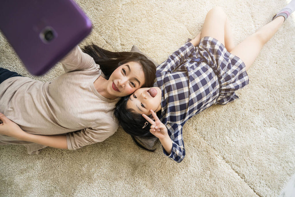 happy Asian Family mother  and daughter making a selfie photo while use  in living room home background. - Fotó, kép