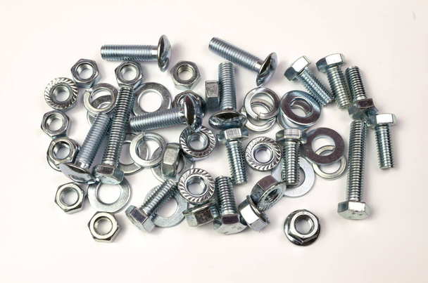 A group of metal products, bolts, nuts, washers is shot close-up. Details are stacked in a small pile. - Foto, afbeelding