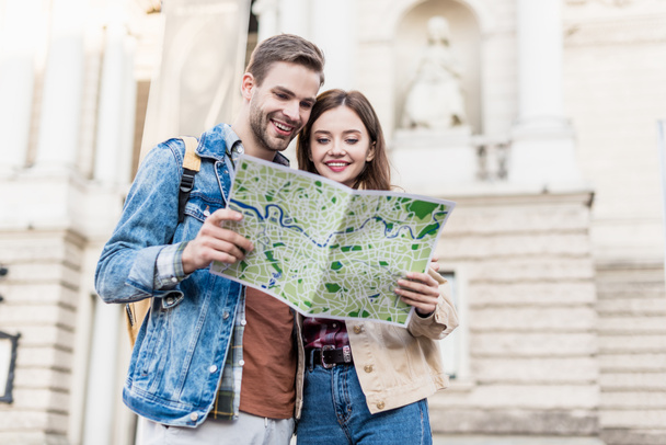 Couple looking at map together and smiling in city - 写真・画像