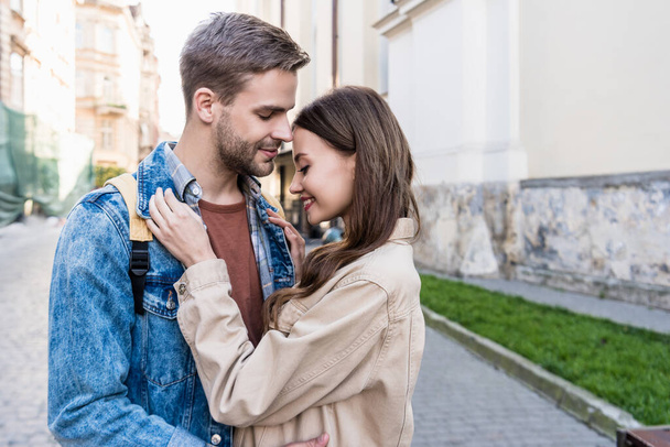 Selective focus of couple hugging and smiling in city - Photo, Image