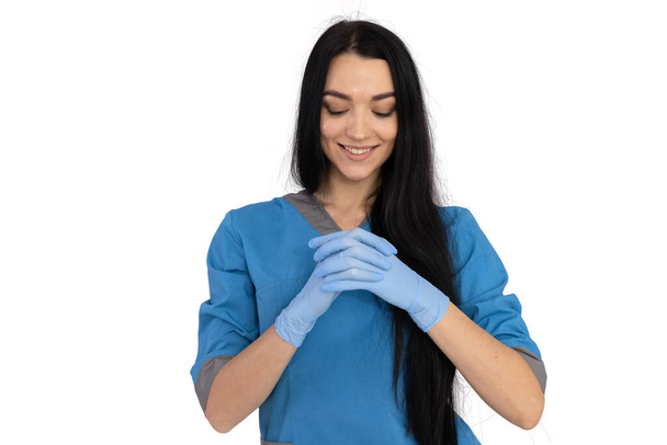 Woman doctor in blue uniform puts on gloves - Photo, Image