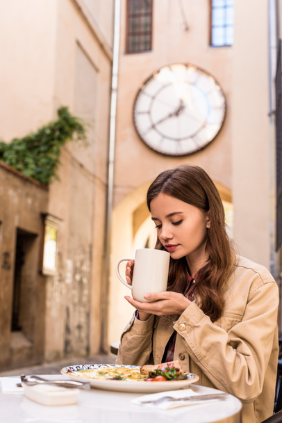 街のカフェでお茶の白いカップを保持する女性の選択的な焦点 - 写真・画像
