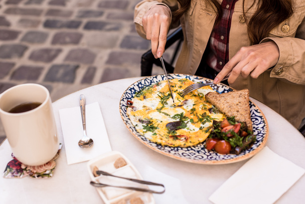 Cropped view of woman eating omelette in cafe - Photo, Image