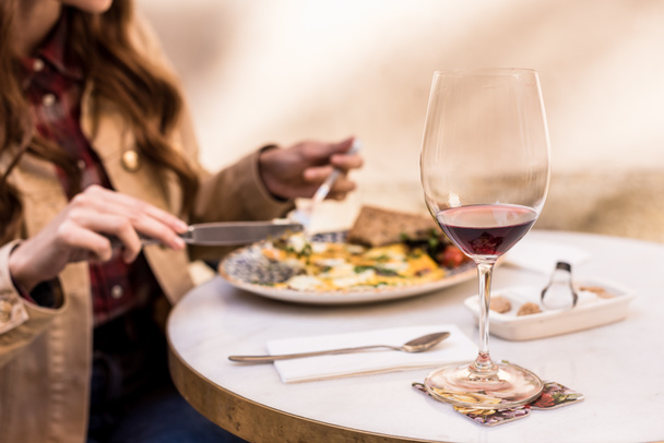 Partial view of woman eating with glass of wine in cafe  - Foto, Imagen