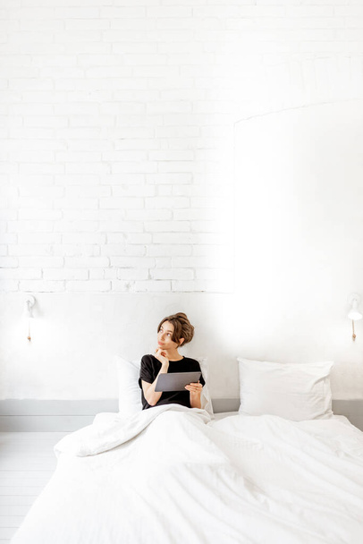 Mulher relaxante com um tablet digital no quarto
 - Foto, Imagem