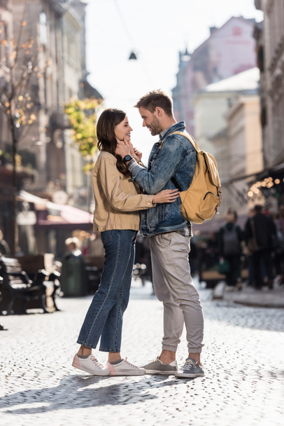 Chłopak i dziewczyna patrzący na siebie uśmiechnięci i przytulający się w mieście Europy - Zdjęcie, obraz