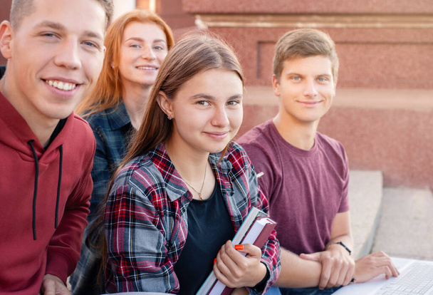Feliz grupo sorridente de estudantes que estudam ao ar livre perto da universidade. Conceito de educação
 - Foto, Imagem