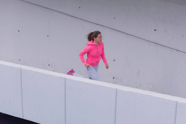 Running woman. Female fitness model training outside in the city. - Foto, afbeelding