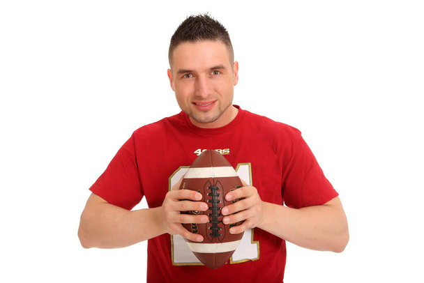 Portrait of a young man holding a football in his hand and smiling kindly into the camera - Foto, afbeelding