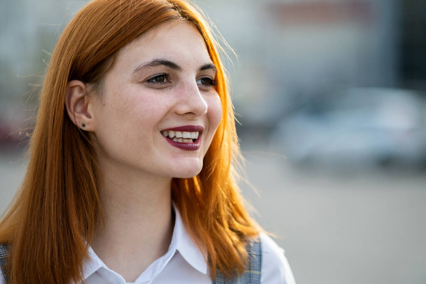 Portrait rapproché d'une adolescente souriante aux cheveux roux et aux yeux clairs
. - Photo, image