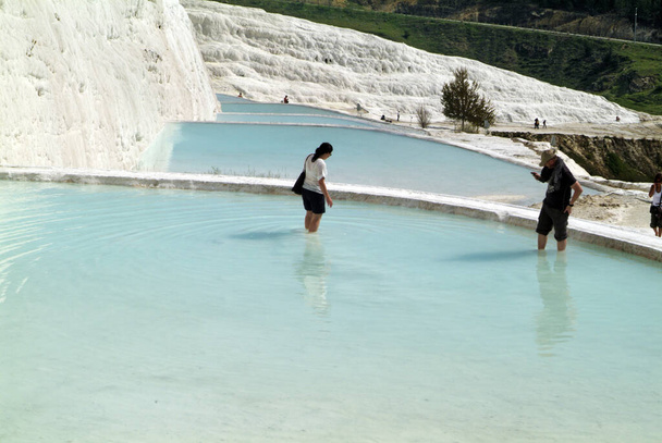 Pamukkale, Turkey - April 09, 2009: Unidentified tourists in the UNESCO World Heritage site, this natural place of interest contains hot springs and travertines, terraces of carbonate minerals left by the flowing water - Fotografie, Obrázek