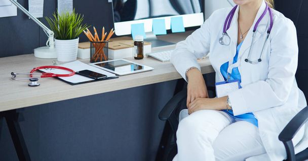 Beautiful young smiling female doctor sitting at the desk - Foto, Imagen